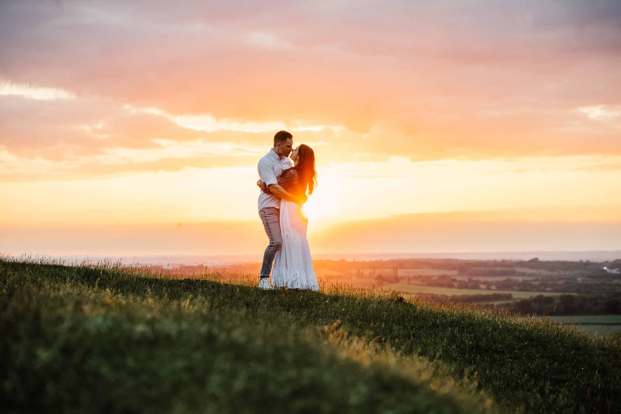 Couple embracing on top of a hill at sunset