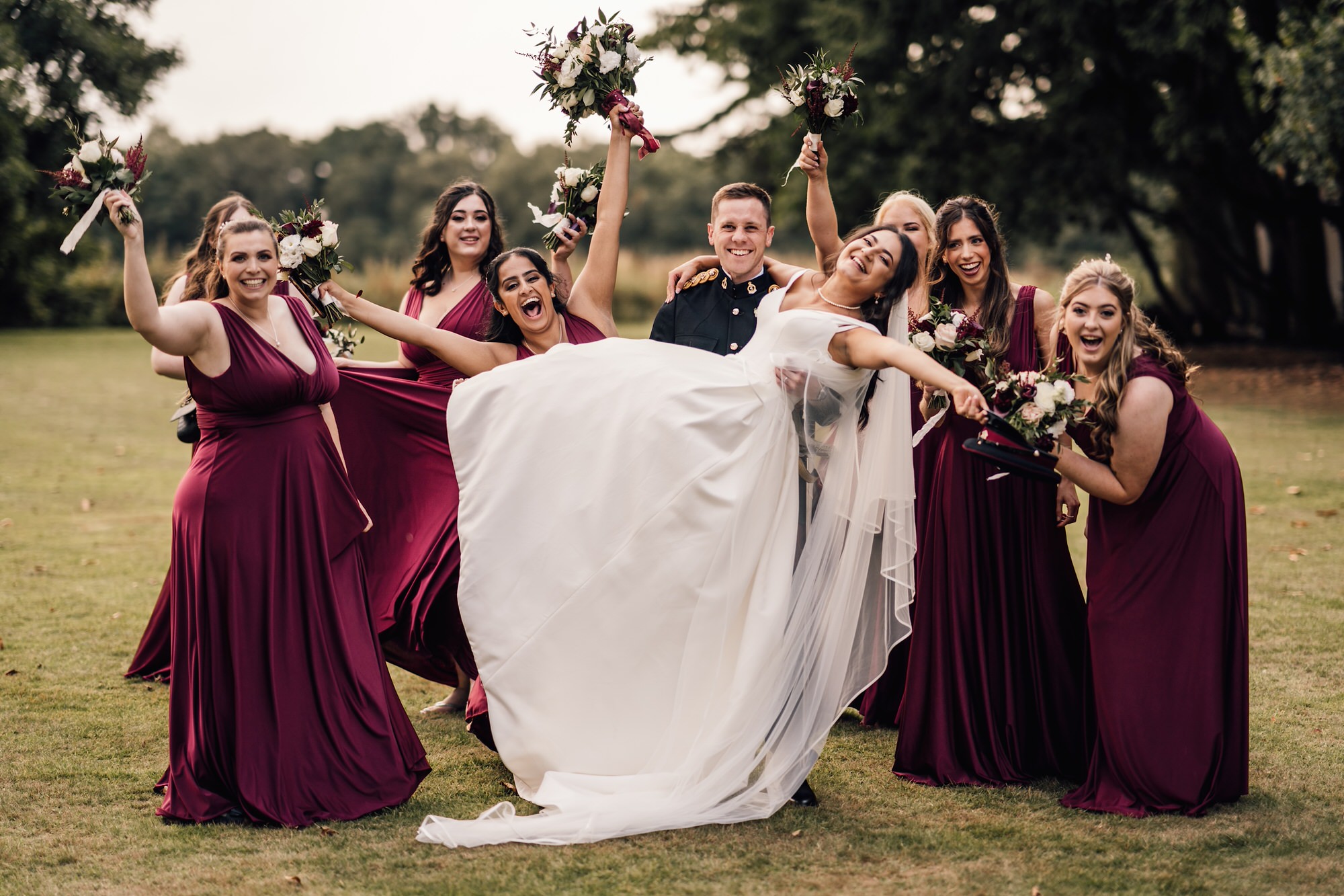 Group photo of bride and groom laughing with bridesmaids 