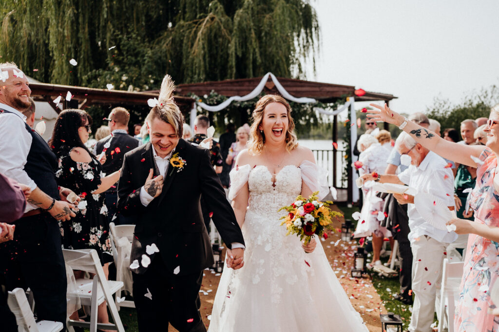 summer wedding with bride and groom confetti photo walking down the aisle 